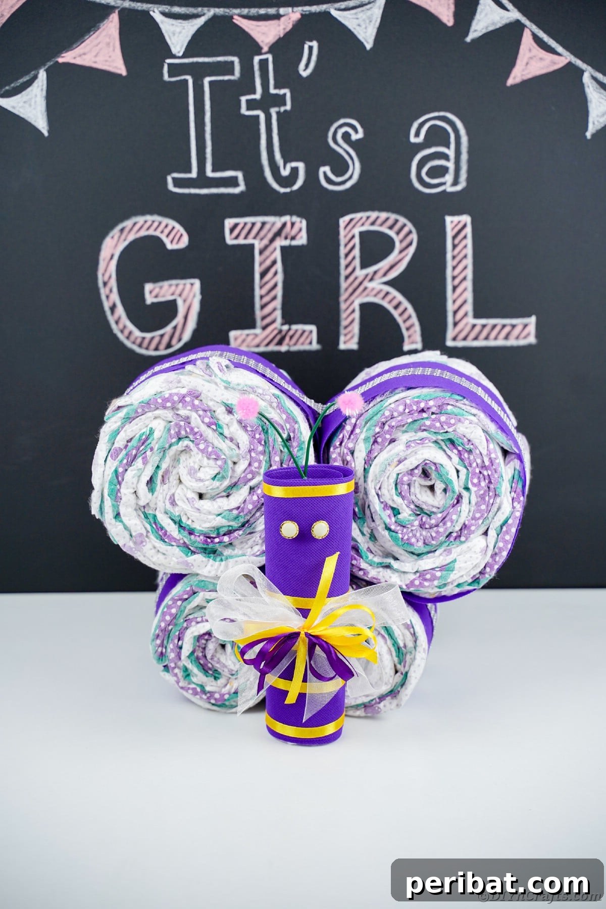 Fluttering Baby Delight: DIY Butterfly Diaper Cake 3 Beautiful purple butterfly diaper cake with a 'It's a Girl' chalkboard message in the background, a delightful baby shower present.