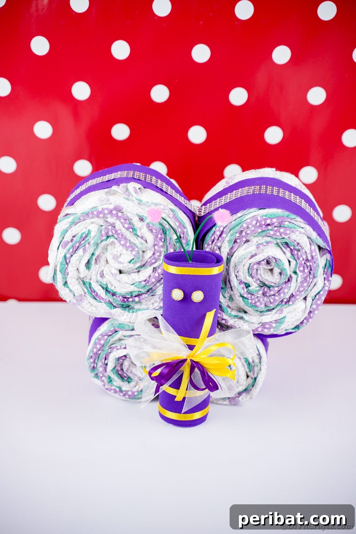 Fluttering Baby Delight: DIY Butterfly Diaper Cake 25 Purple butterfly diaper cake against a charming red and white polka dot wall, ideal for playful baby nursery decor.