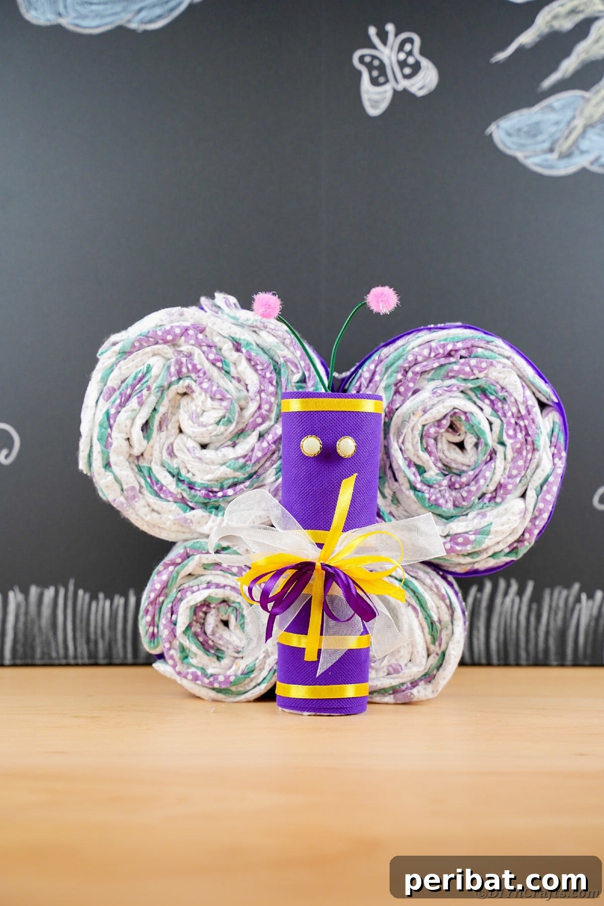 Fluttering Baby Delight: DIY Butterfly Diaper Cake 27 Purple diapers artfully arranged into a butterfly shape, displayed in front of a rustic chalkboard, a charming baby shower decoration.