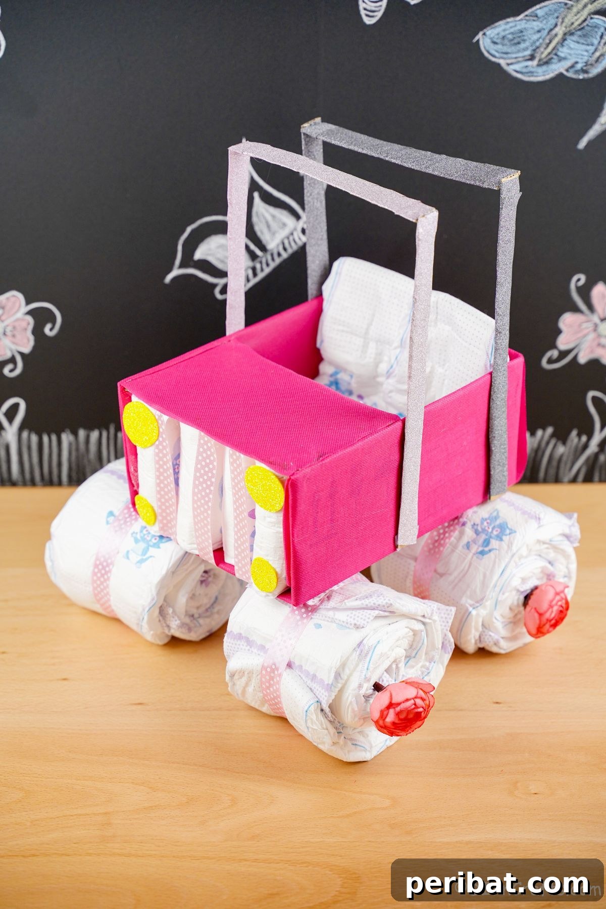 pink diaper cake on wood table by chalkboard