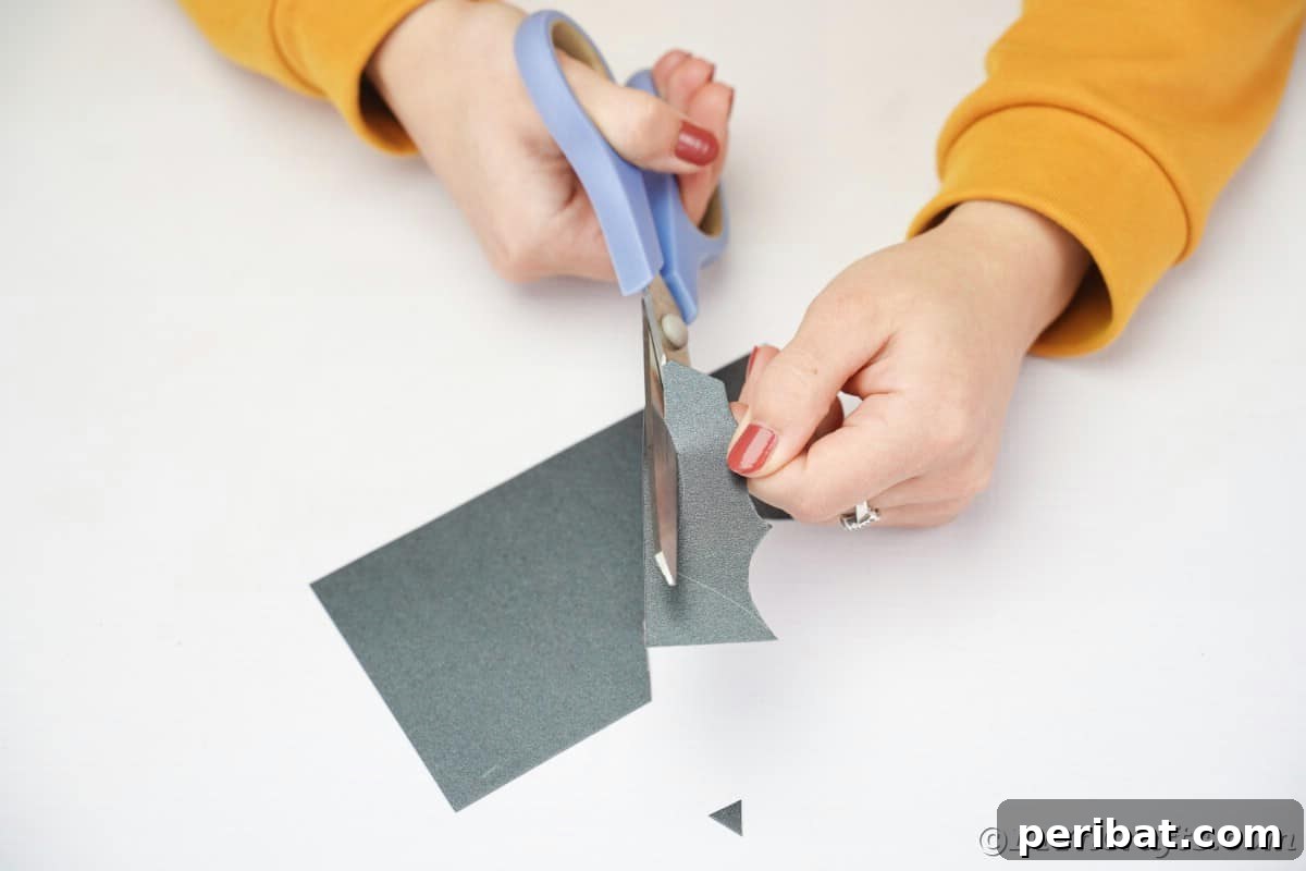 Cutting bat wings out of black paper using blue scissors