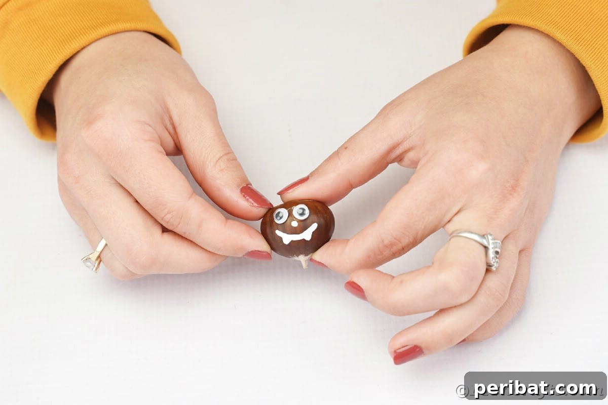 Woman holding chestnut with face painted on it