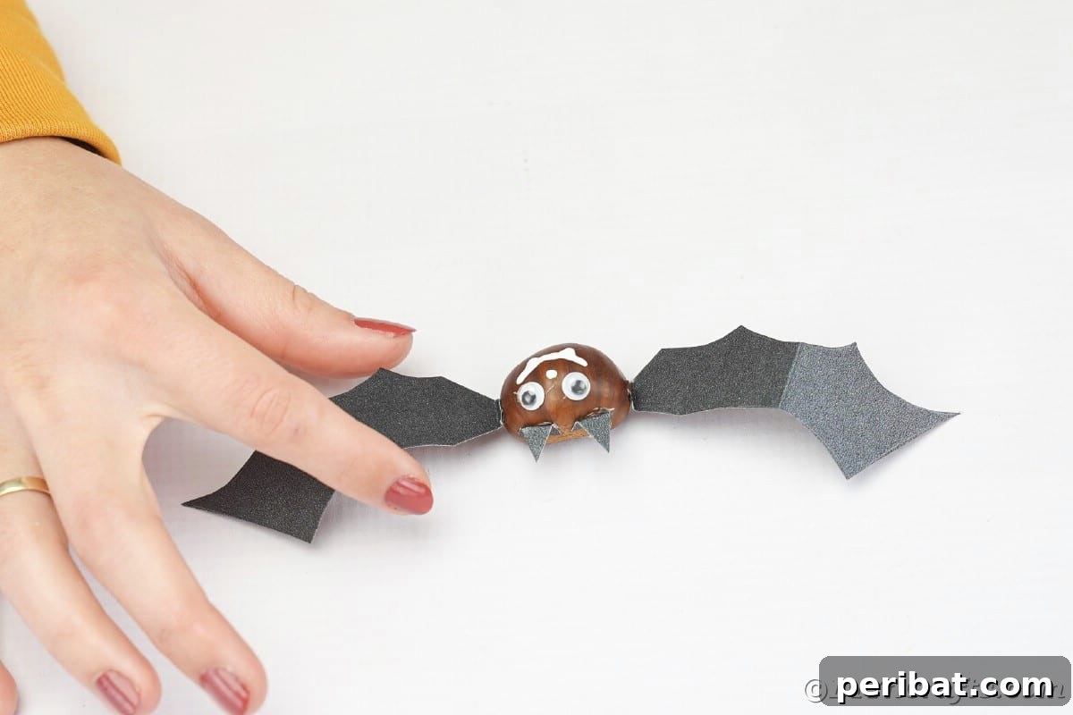 Hand holding paper wing against chestnut bat face