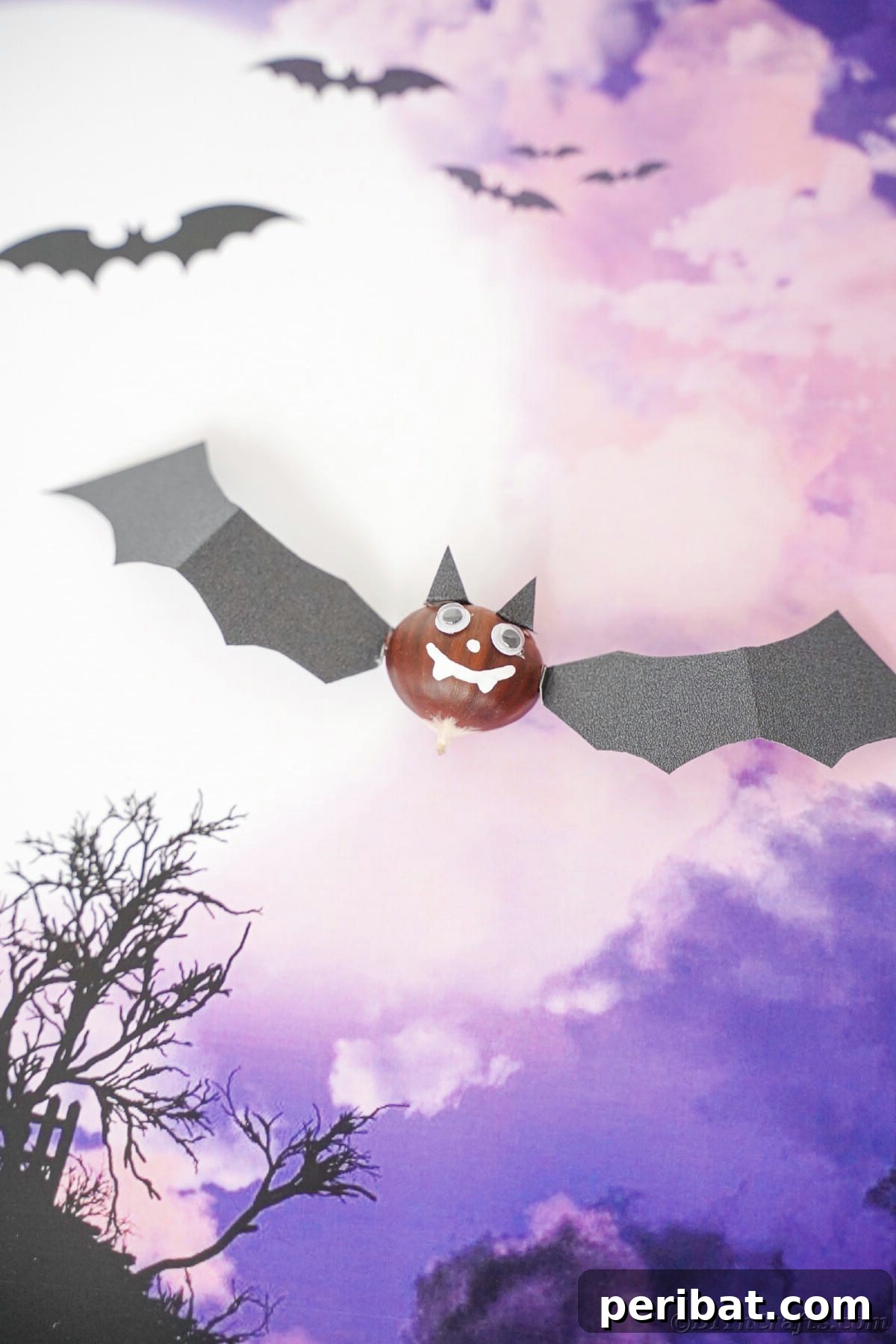 Bat decoration laying on top of purple scrapbook paper 