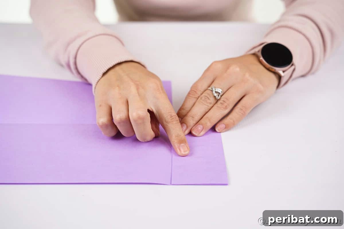 Fan-tastic Hedgehog Craft for Kids 11 A woman's hands meticulously folding and gluing purple paper, demonstrating how to secure the head section of the paper hedgehog.