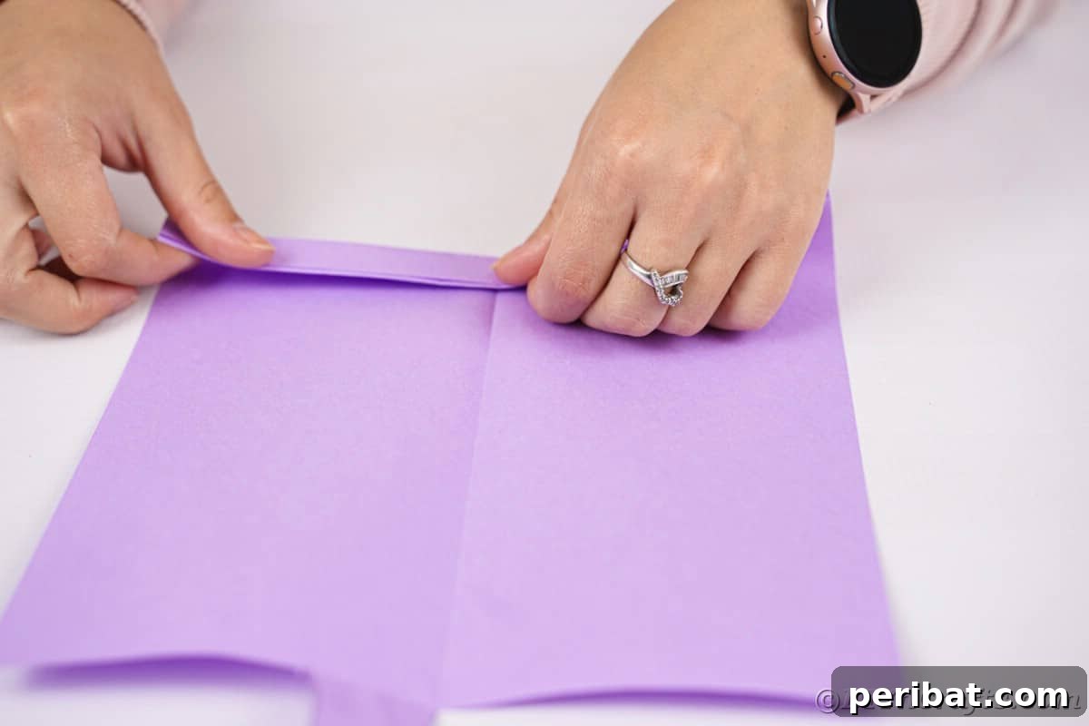Fan-tastic Hedgehog Craft for Kids 14 Two hands skillfully folding purple paper in an accordion style, demonstrating the creation of the fan body.
