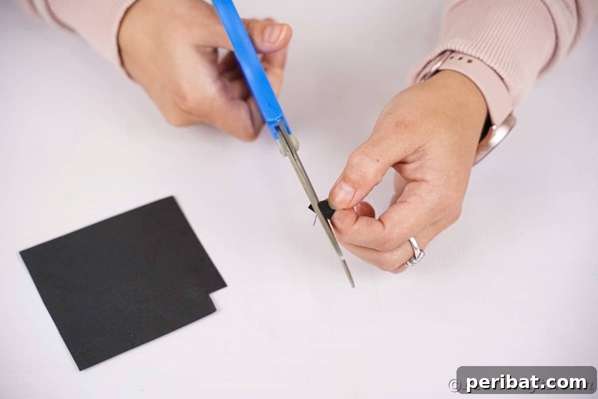 Fan-tastic Hedgehog Craft for Kids 17 A woman cutting a small, perfectly round circle from black paper to create the hedgehog's nose.