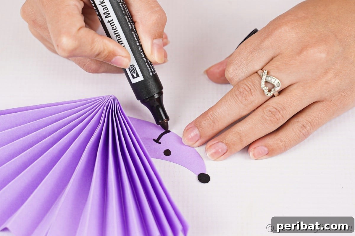 Fan-tastic Hedgehog Craft for Kids 19 A hand drawing a smile and an eye onto the purple paper hedgehog's face with a black marker, adding character.