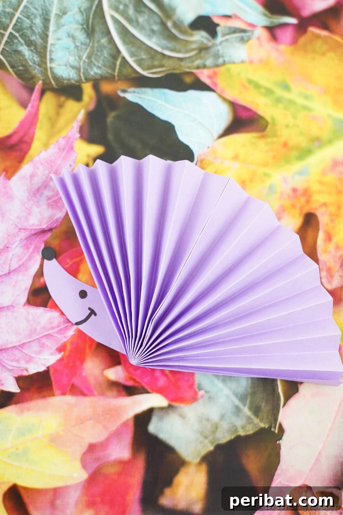 Fan-tastic Hedgehog Craft for Kids 27 A purple paper fan hedgehog resting on a decorative fake leaf, emphasizing its decorative potential.