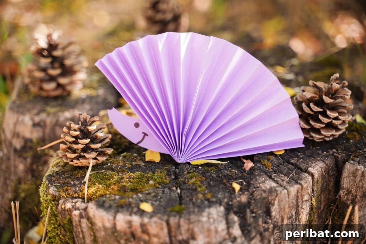Fan-tastic Hedgehog Craft for Kids 5 A delightful paper fan hedgehog placed on a moss-covered tree stump with pinecones, showcasing its natural decor potential.