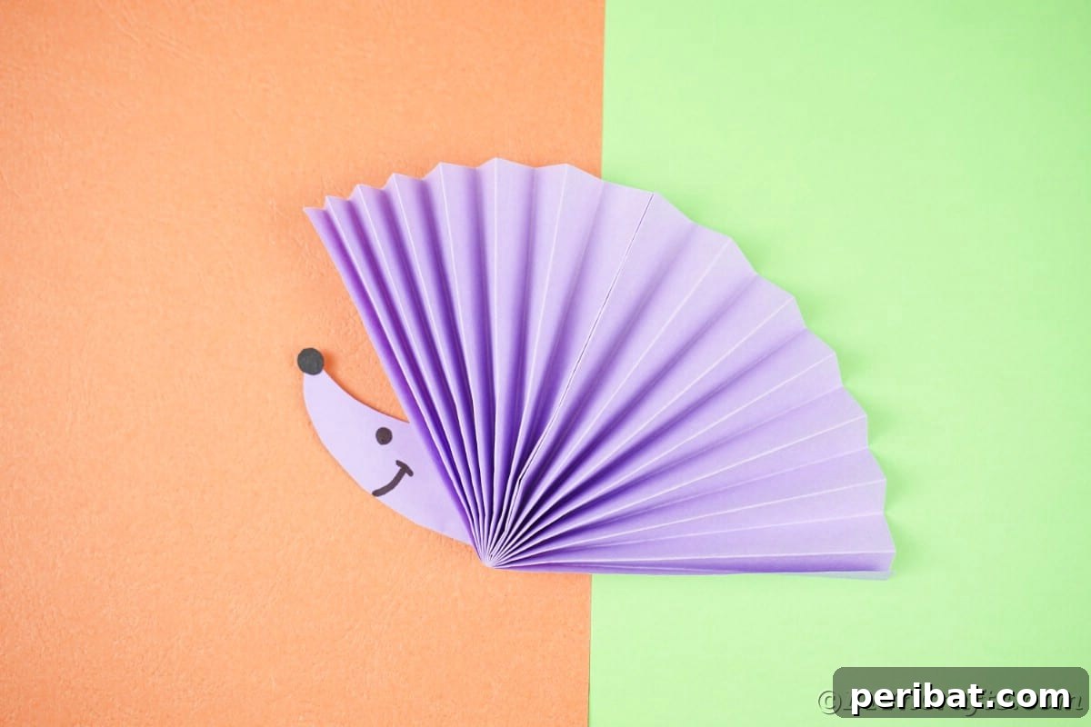 Fan-tastic Hedgehog Craft for Kids 7 A vibrant purple paper fan hedgehog with a cute face, set against a cheerful green and orange background, highlighting its playful design.