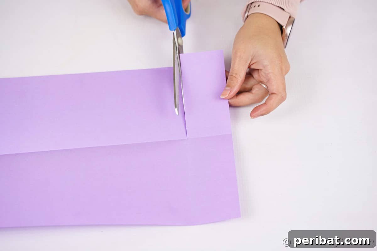 Fan-tastic Hedgehog Craft for Kids 10 A hand precisely cutting purple paper with blue scissors along a fold line, illustrating the initial shaping process.