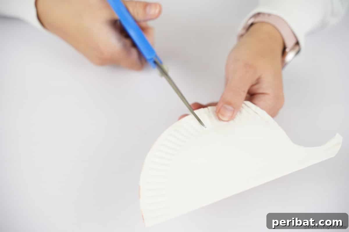 Hand using scissors to cut top of paper plate