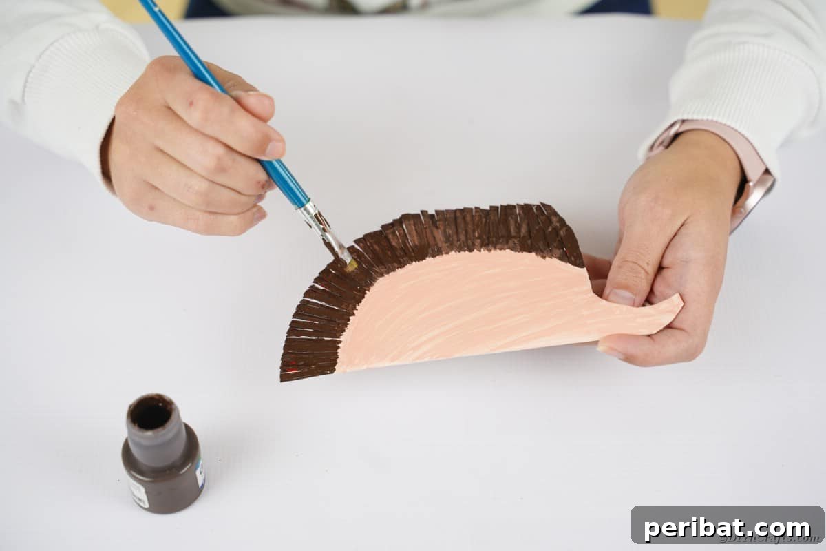 Hand painting dark brown on top of paper plate