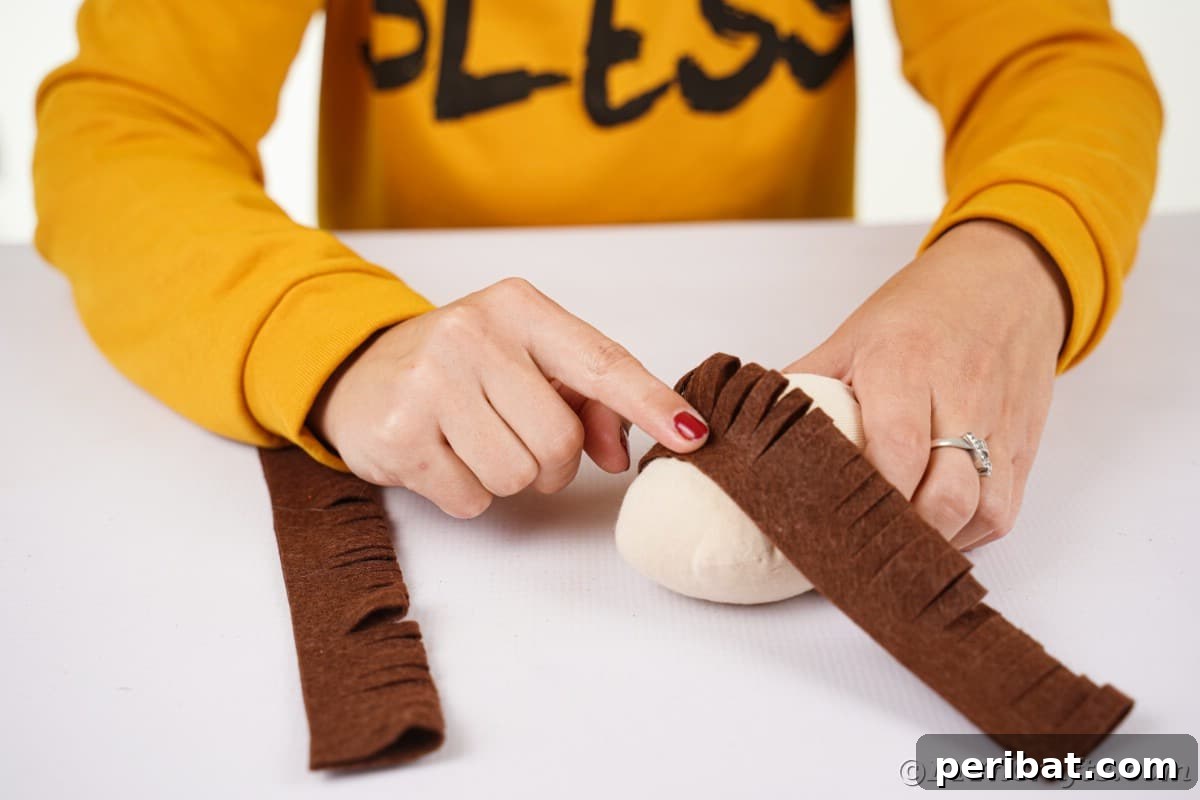 Effortless No-Stitch Fabric Hedgehog Creation 15 Hands meticulously glue a fringed felt strip onto the stuffed sock body, carefully positioning the 'spikes' to face the back of the hedgehog.