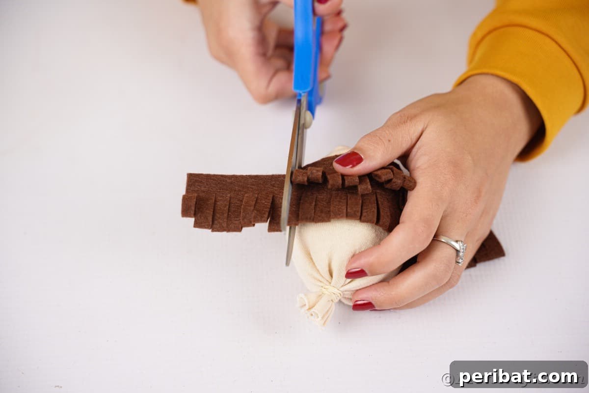 Effortless No-Stitch Fabric Hedgehog Creation 16 Scissors meticulously trim excess felt from the side of the hedgehog body, refining its shape and ensuring a neat finish to the fabric 'spikes'.