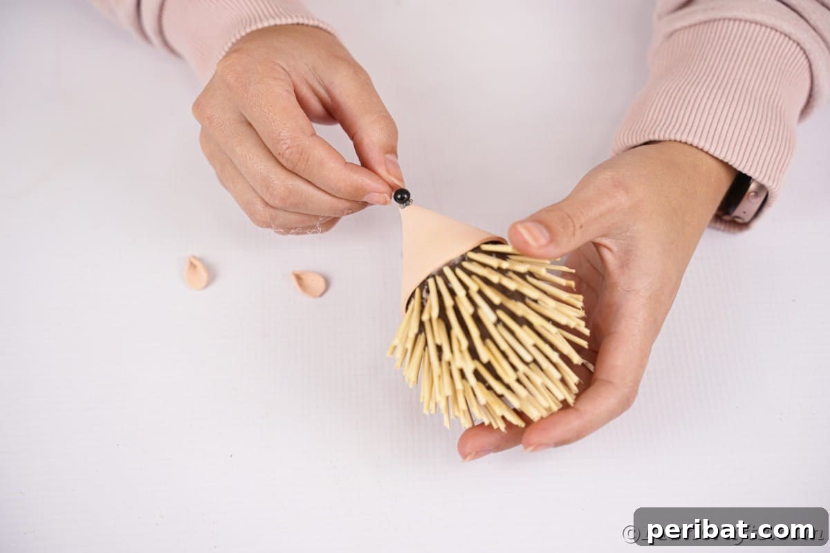 Rustic Foam Hedgehog: An Easy Autumn Craft for Kids 16 Hand putting bead on nose of hedgehog toy