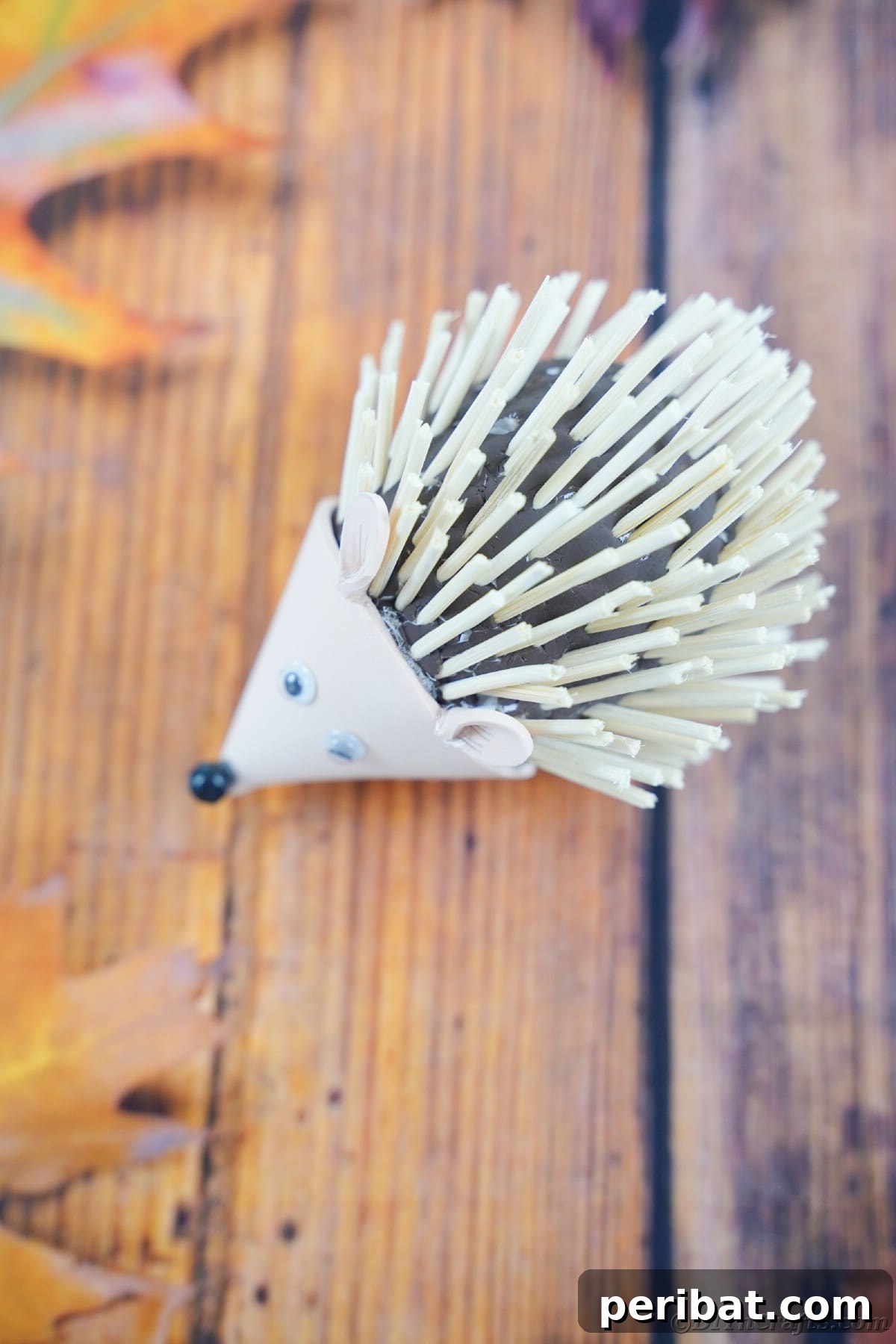 Rustic Foam Hedgehog: An Easy Autumn Craft for Kids 4 Wood slat table with fall leaves and toy hedgehog on top