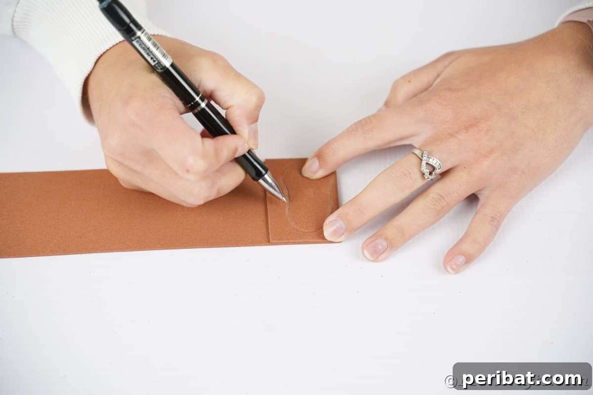 An adult's hand holds a pen, tracing small, rounded shapes onto brown foam paper for the hedgehog's features