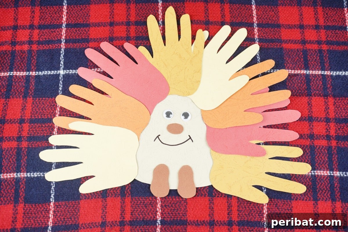 Finished handprint hedgehog in warm autumn tones, resting on a cozy plaid fabric
