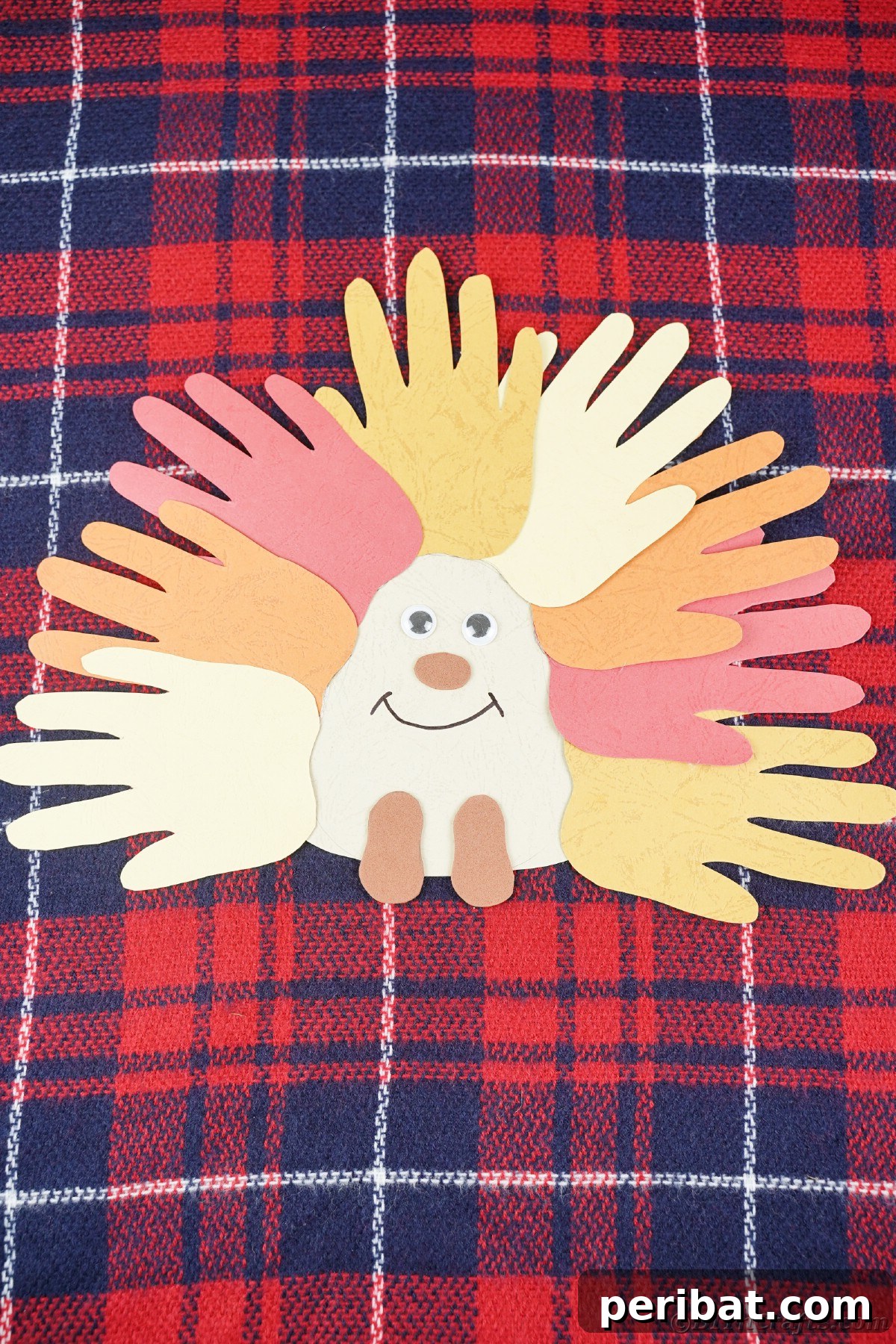 A delightful handprint hedgehog resting on blue and red plaid fabric, showcasing its vibrant fall colors