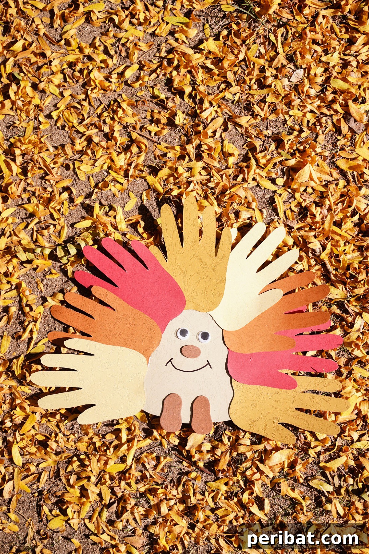 A charming handprint paper hedgehog craft settled among vibrant fallen yellow leaves on the ground