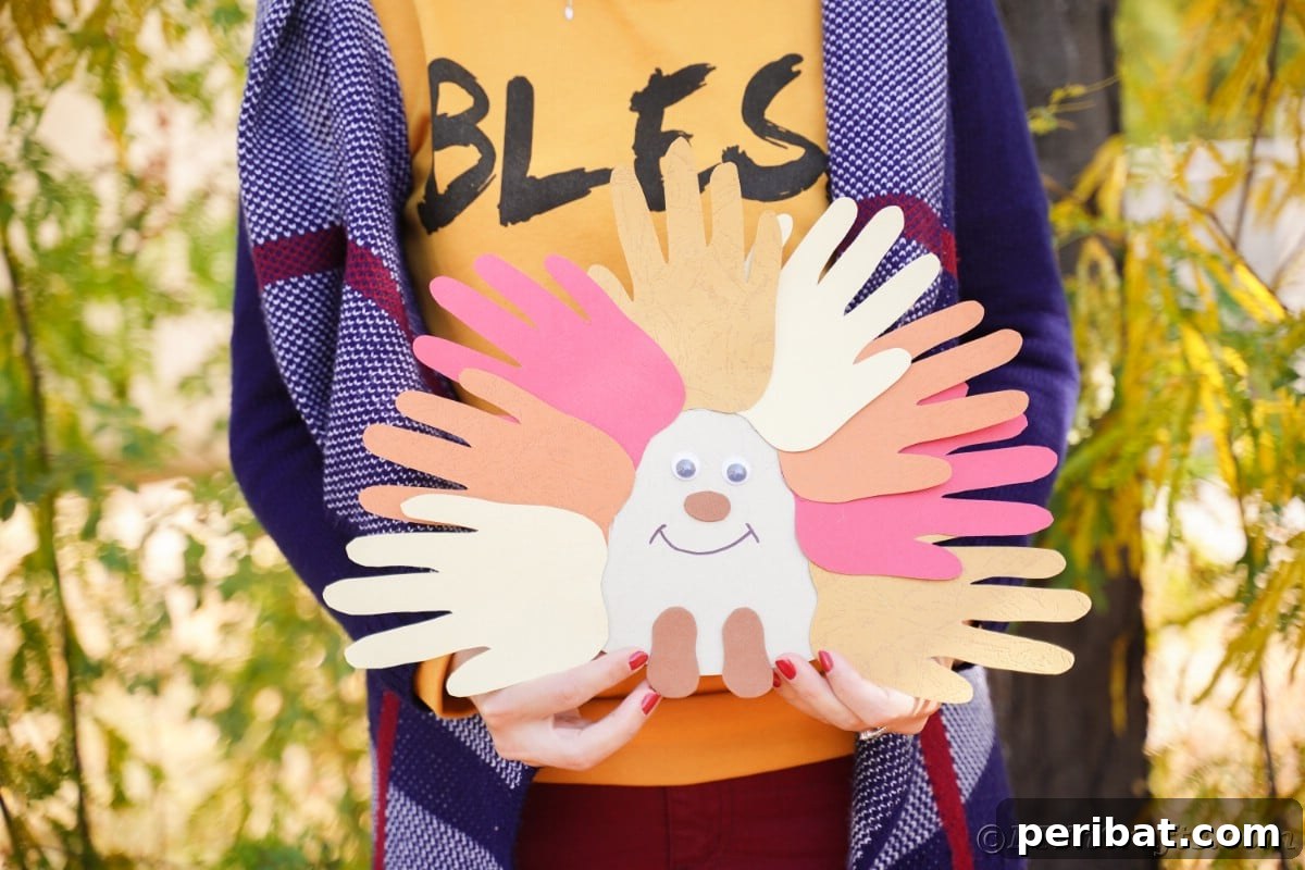 Close-up of a woman's hand gently holding a finished handprint hedgehog craft