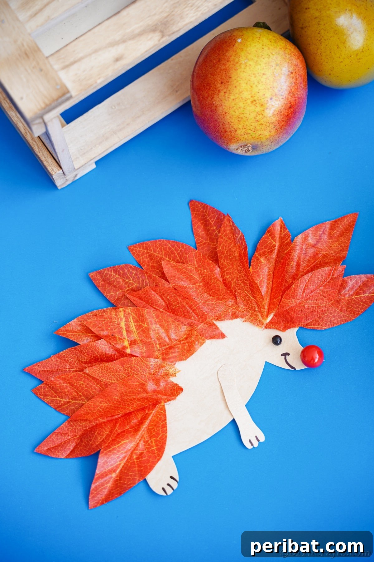 Fake leaf hedgehog on blue paper, a delightful craft for autumn decor.