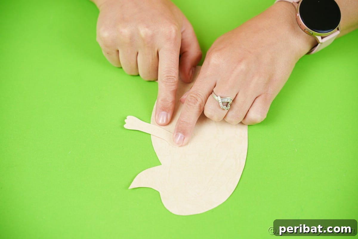 Fingers holding arm shaped paper on side of hedgehog shaped paper, securing it in place.