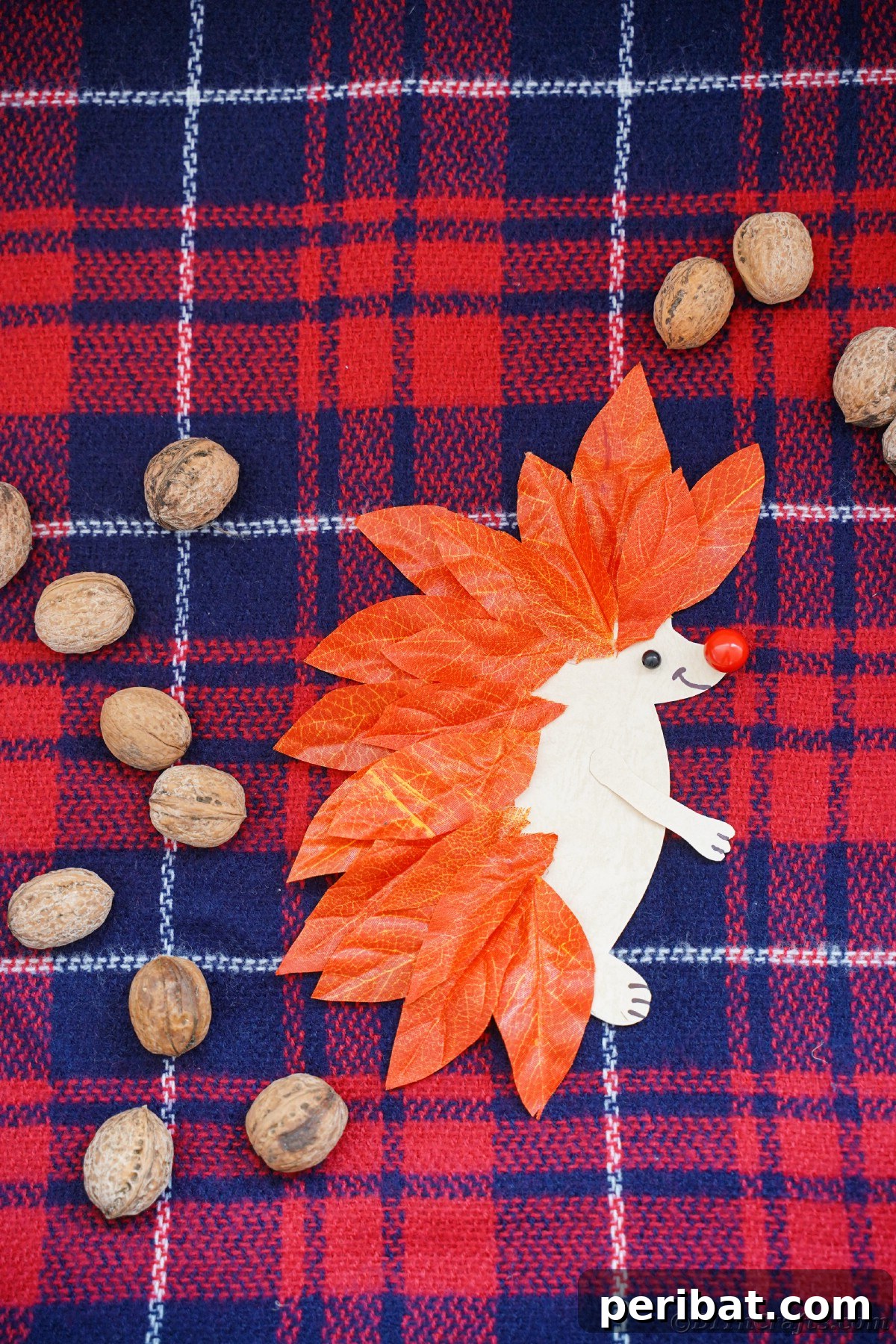 Red and blue plaid fabric under paper hedgehog, highlighting cozy autumn aesthetics.