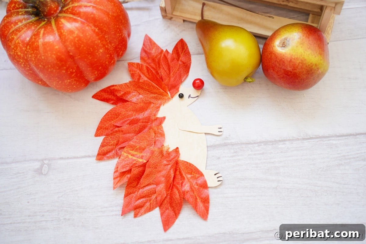 White wood surface with fake pumpkin and pears next to paper hedgehog, showcasing fall decor.