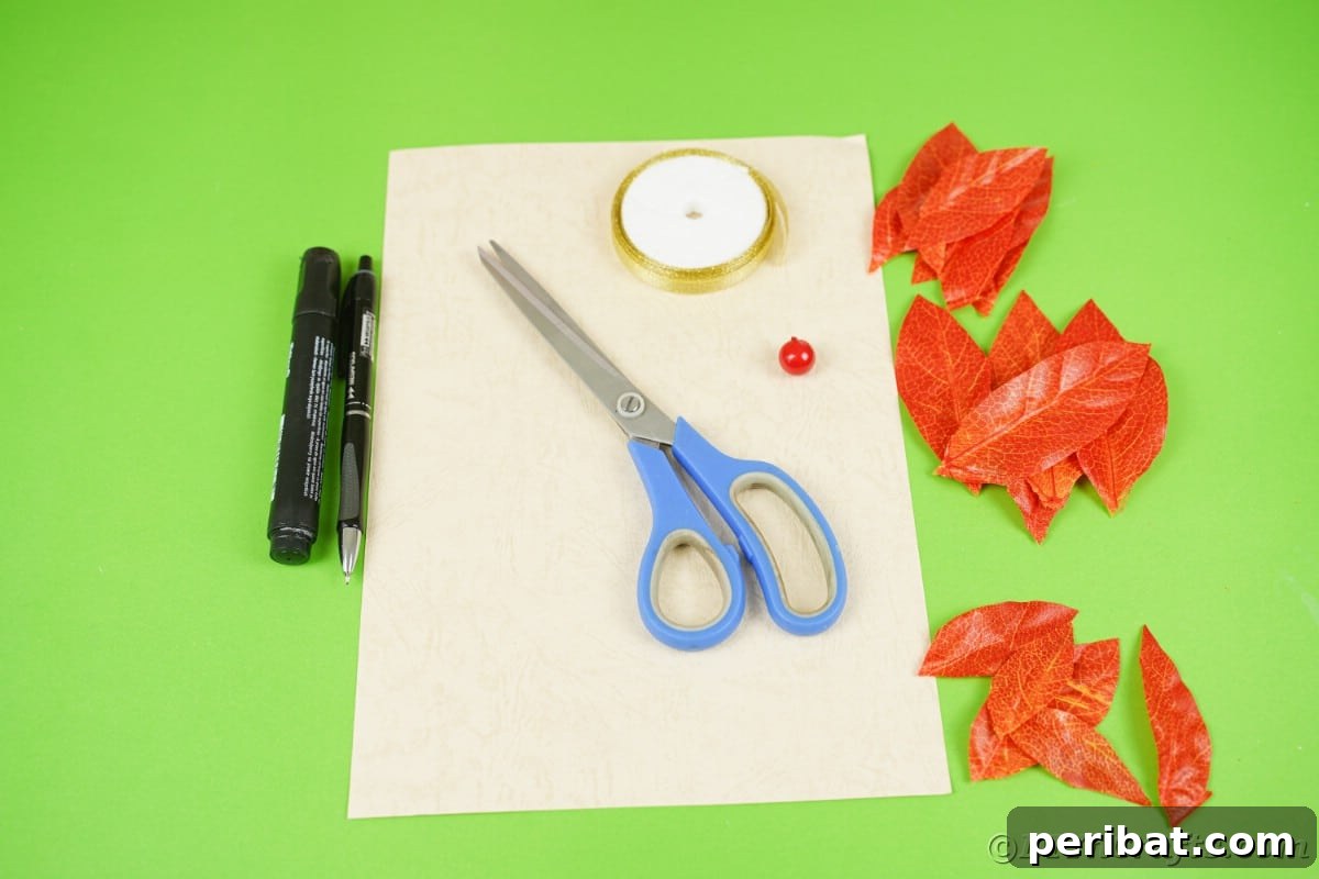 Cream paper scissors markers and orange fake leaves on green surface, showing craft supplies.