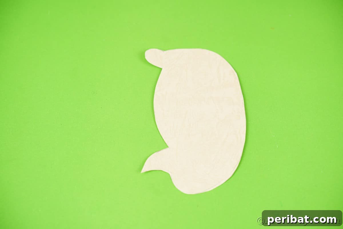 Cream paper hedgehog body shape on green surface, freshly cut.