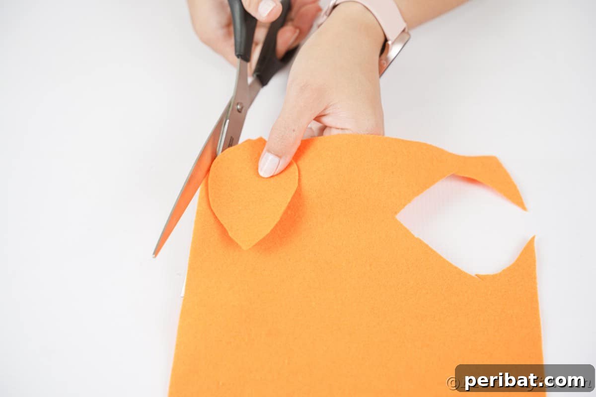 Hand cutting a leaf out of orange felt
