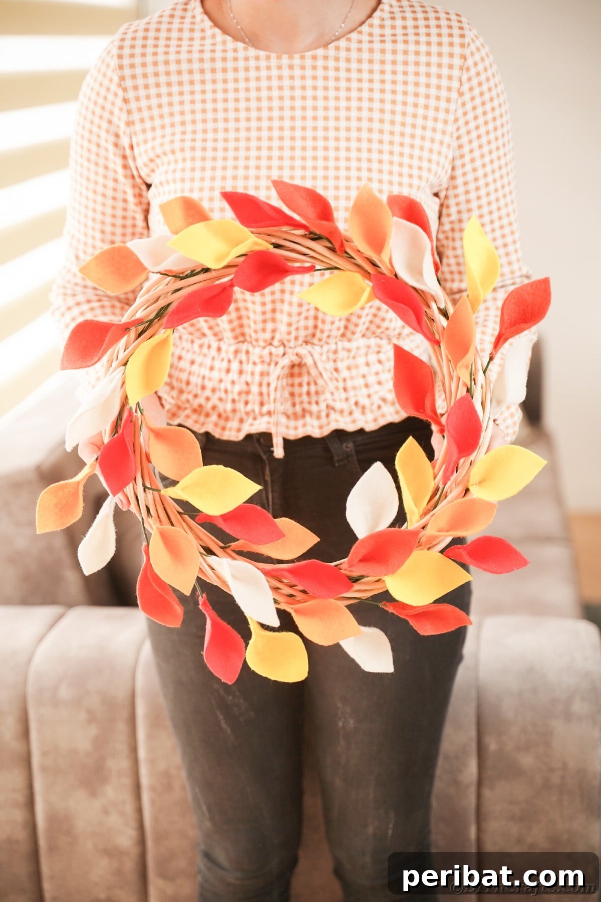 Woman holding fall colored leaf wreath