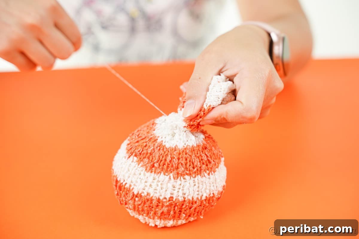 Cozy Sock Pumpkins Fall Home Decor 13 Stuffed sock being tied off at top with thread, showing the sealing of the pumpkin's base