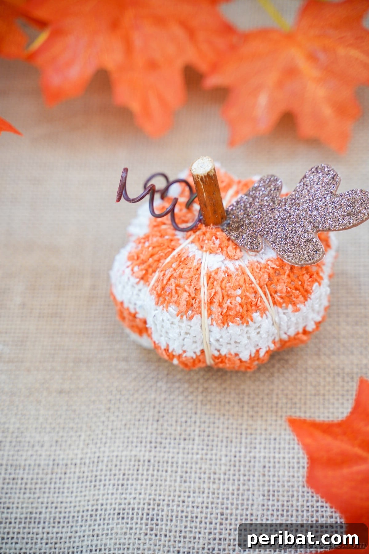Cozy Sock Pumpkins Fall Home Decor 22 Striped fabric pumpkin on tan burlap with fake leaves, evoking a rustic and warm fall ambiance