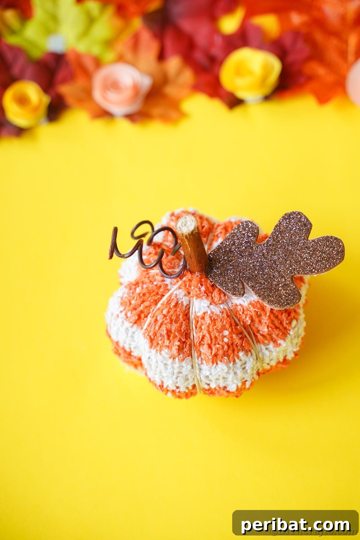 Cozy Sock Pumpkins Fall Home Decor 5 Orange and white striped pumpkin sitting on yellow paper, a vibrant contrast against autumn hues