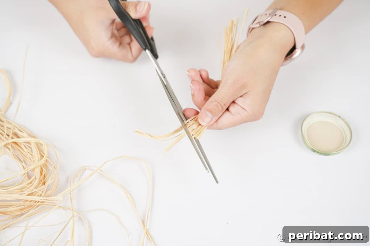 Farmhouse Burlap Owl Wreath 11 Hand holding black scissors cutting raffia, preparing materials for the owl's eyes