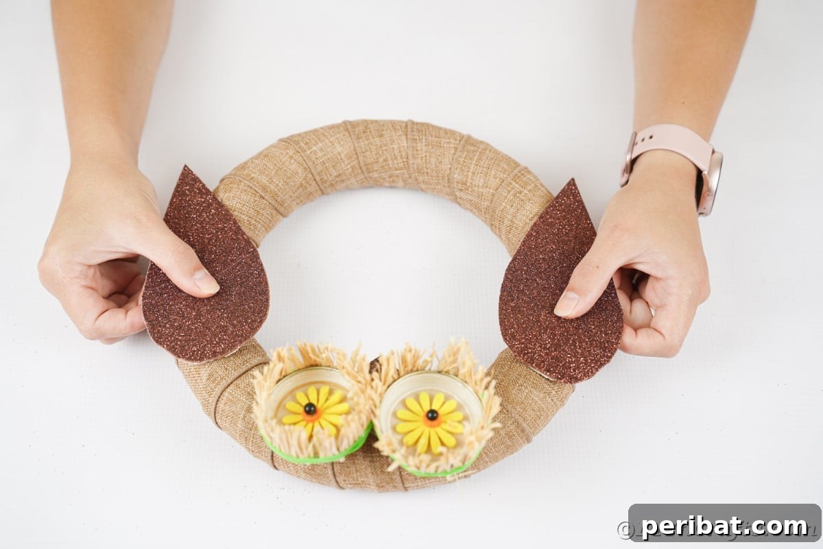 Farmhouse Burlap Owl Wreath 20 Hands placing wings on sides of owl wreath, adding the final decorative elements