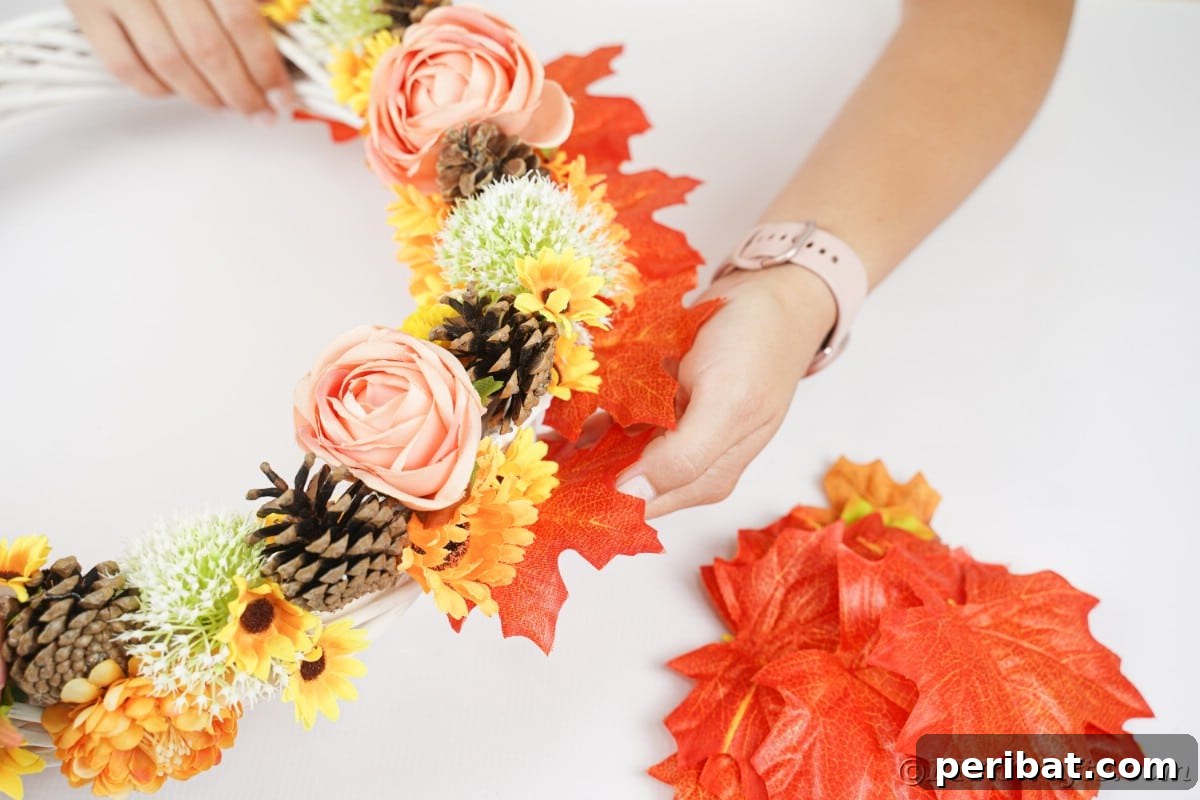 Charming Fall Blossom & Pinecone Wreath 11 Hand gluing leaves on back of wreath