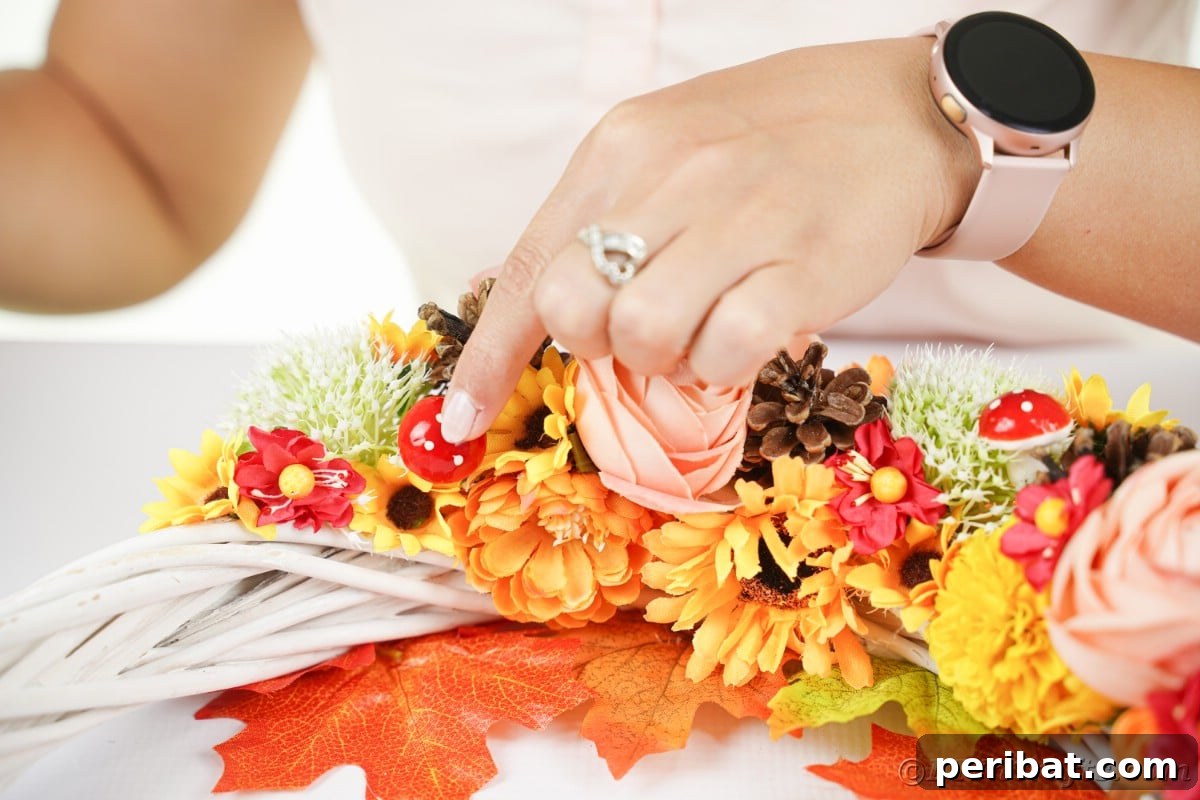 Charming Fall Blossom & Pinecone Wreath 12 Hand putting mushroom onto wreath