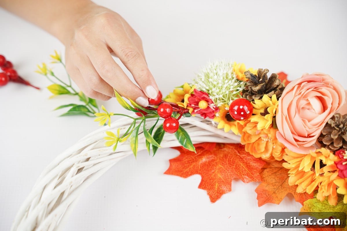 Charming Fall Blossom & Pinecone Wreath 13 Hand putting berries onto wreath