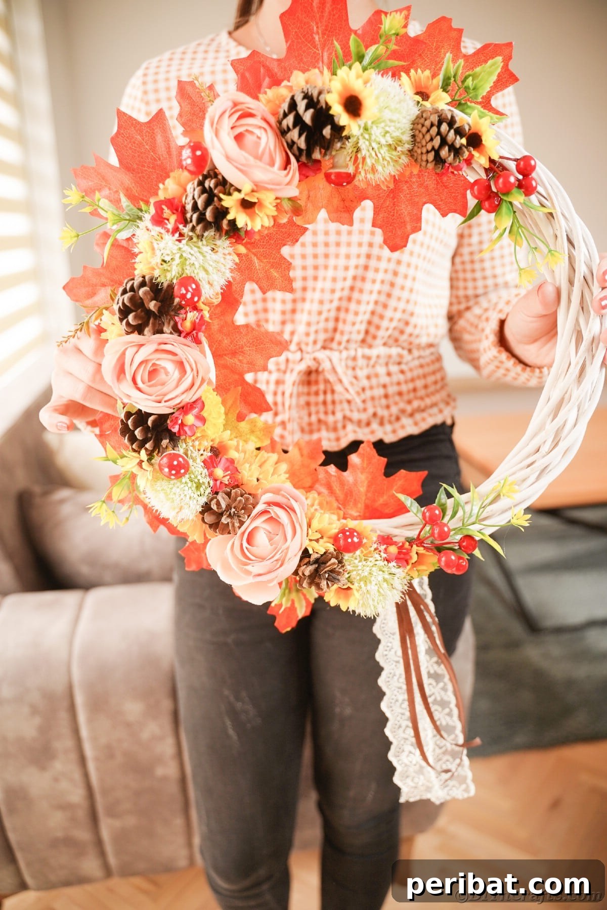 Charming Fall Blossom & Pinecone Wreath 18 Woman in black pants holding floral wraeth