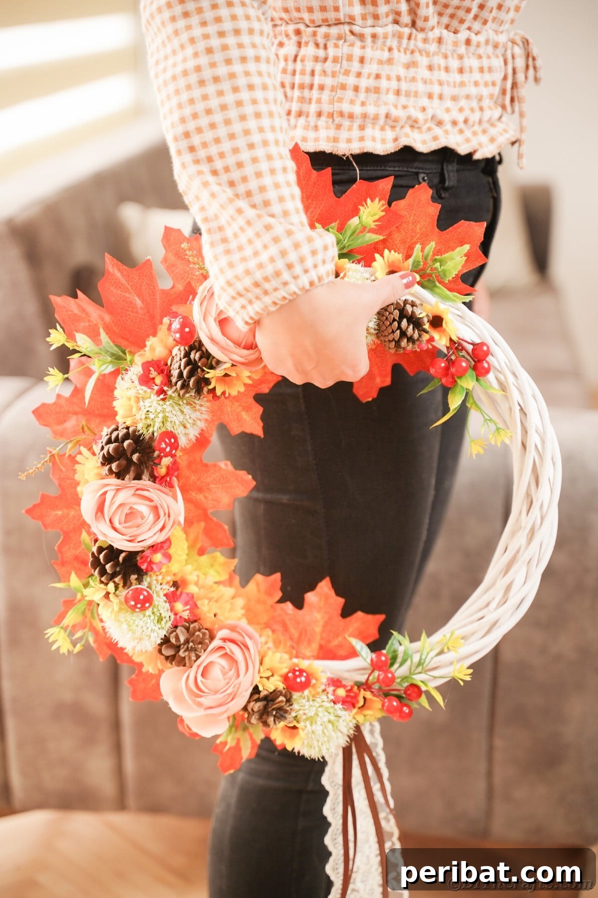 Charming Fall Blossom & Pinecone Wreath 6 Fall wreath being held on the side by woman in black pants