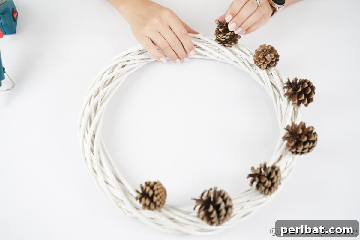 Charming Fall Blossom & Pinecone Wreath 8 Pinecones being glued on one side of a wreath