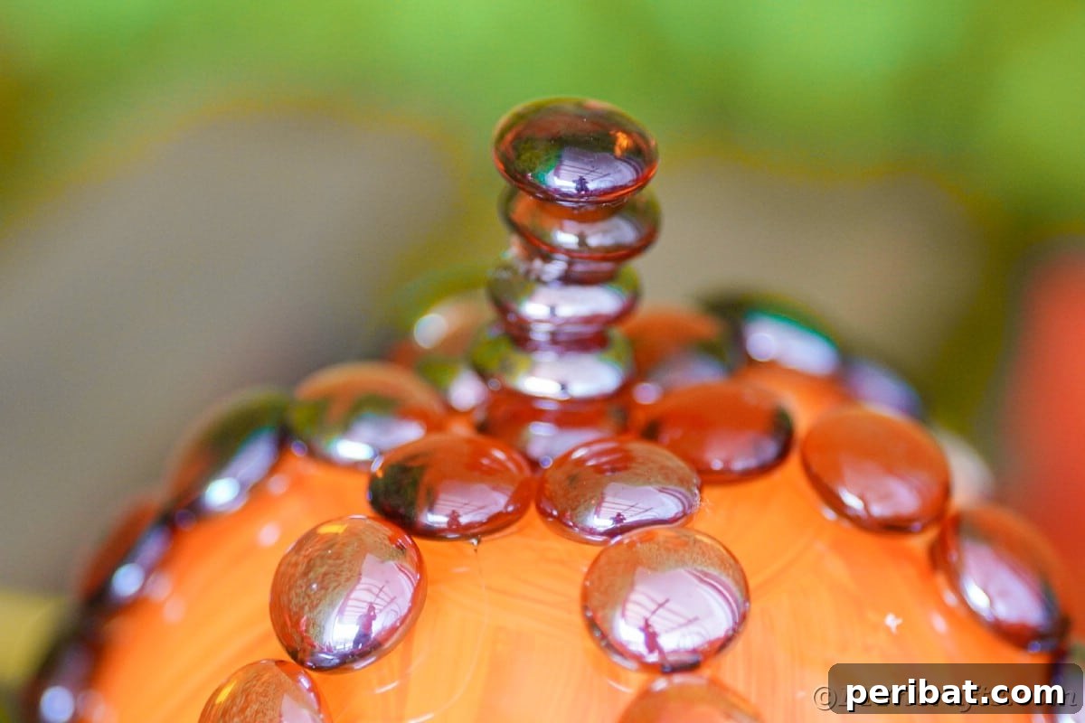 Close-up of brown glass rocks meticulously stacked and glued together on top of the glass pumpkin, forming a textured and realistic stem.