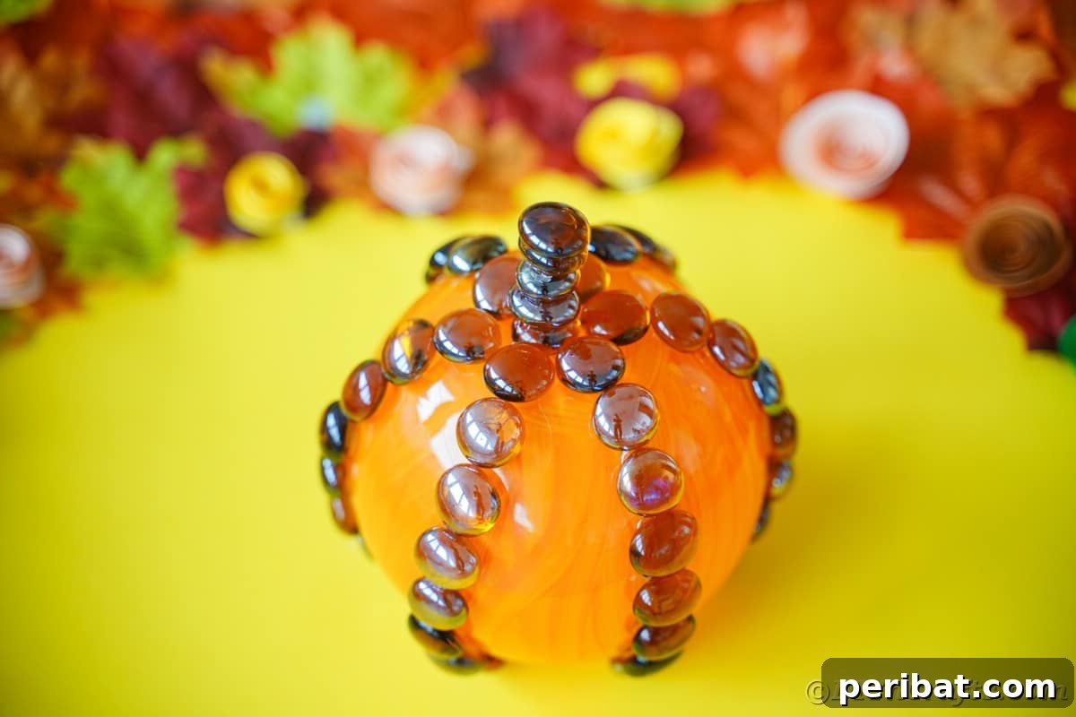 A vibrant glass pumpkin decoration rests on a bright yellow surface, ready to be a focal point of fall decor, highlighting its cheerful autumn aesthetic.