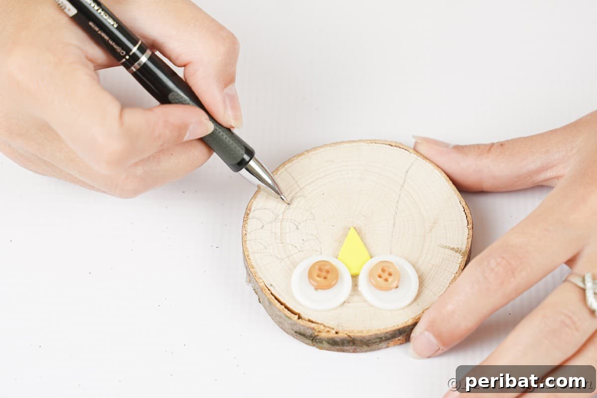 A hand expertly draws a detailed owl wing design with a pen on a rustic wood slice, outlining the intricate feather patterns.