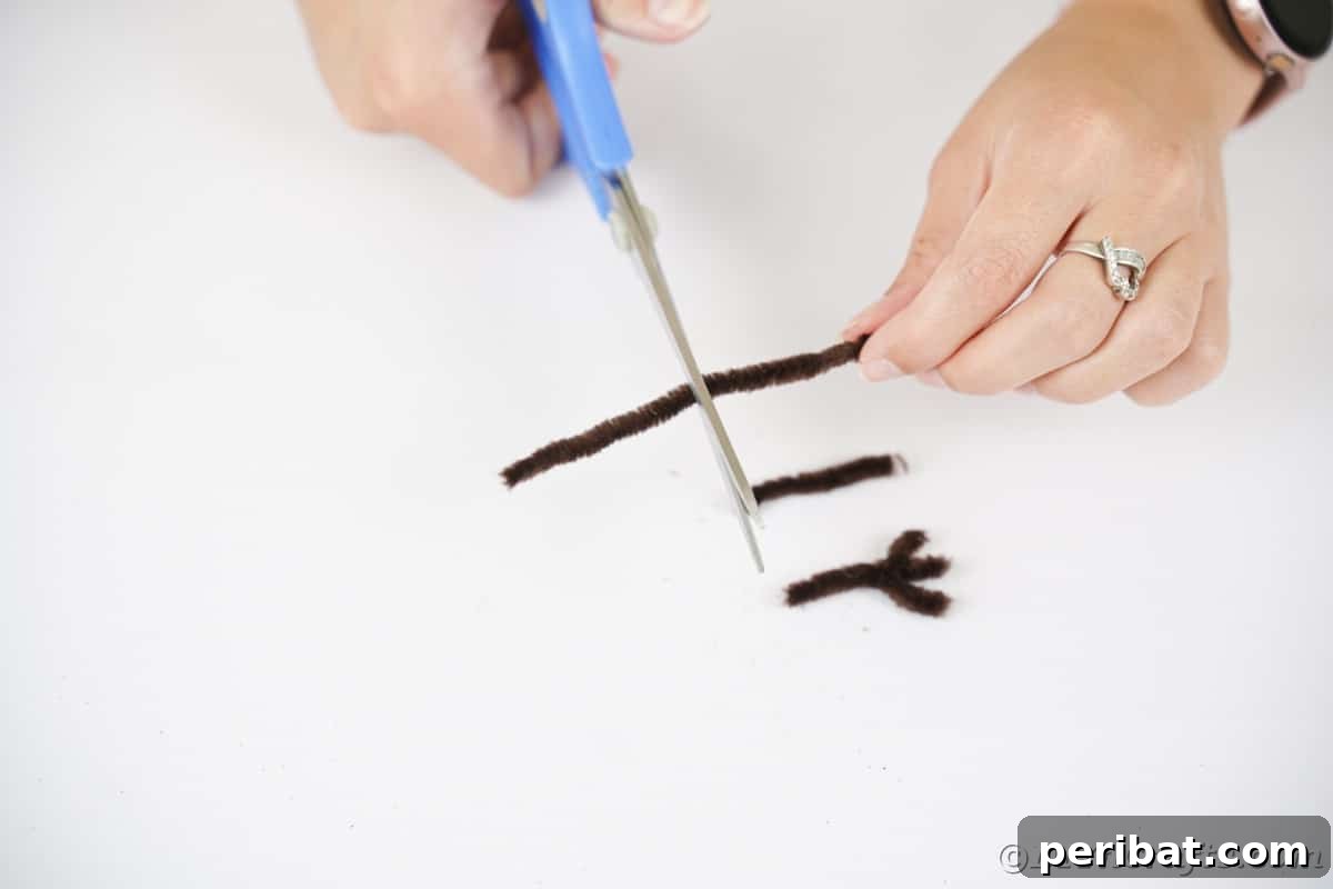 A pair of blue scissors neatly cuts brown pipe cleaners into uniform segments, preparing them to form the owl's charming feet.